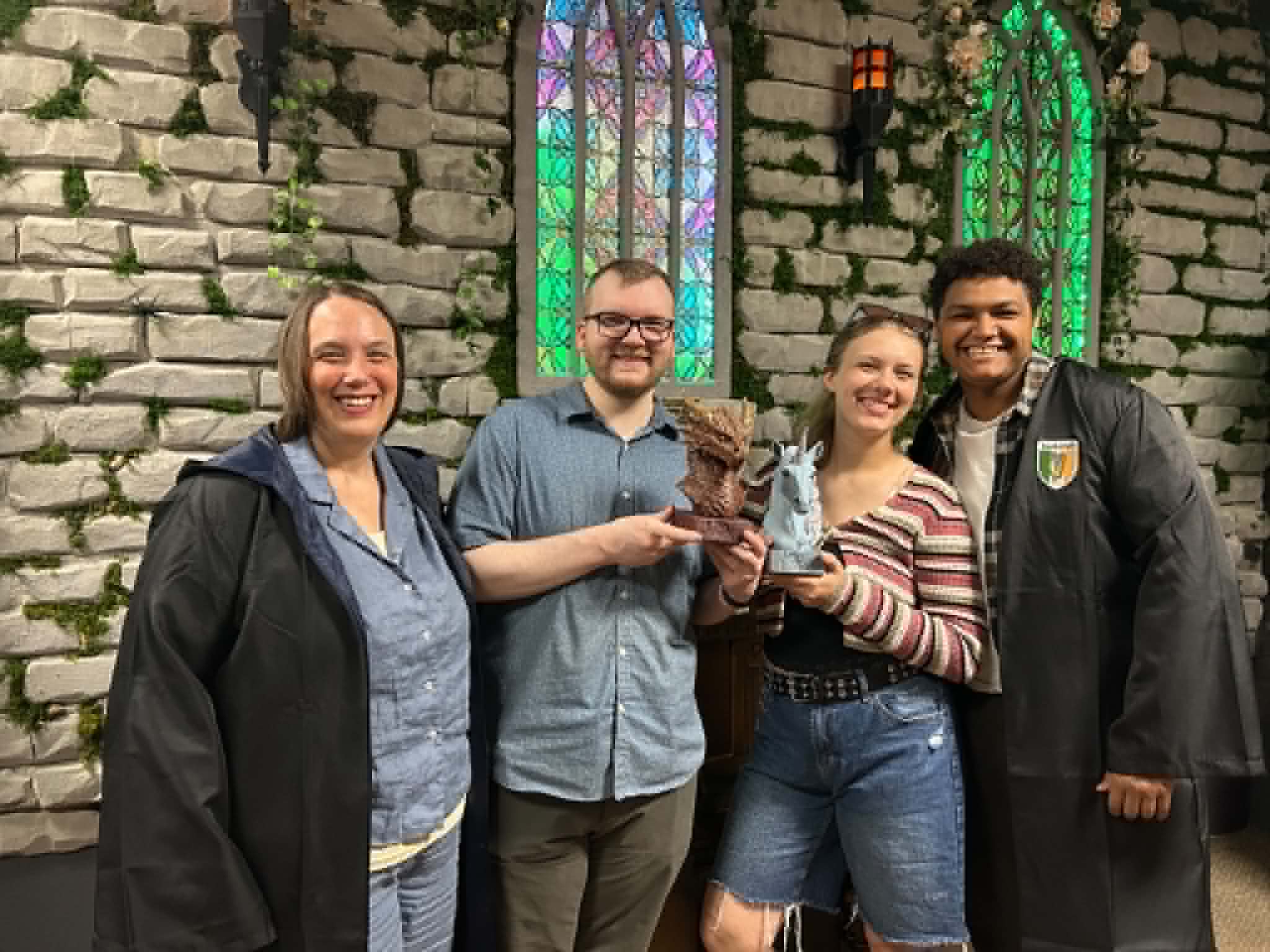 A group of guests celebrating with props inside Griffin's Door at Twisted Escape Rooms, Vancouver, WA